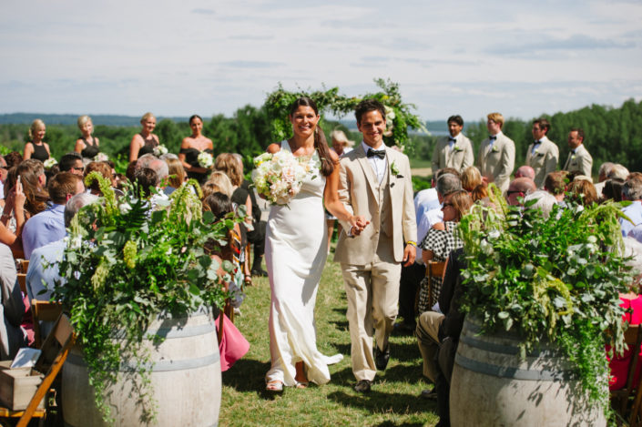 Bride and groom walking up the aisle at a summer wedding in our scenic hilltop vineyard.