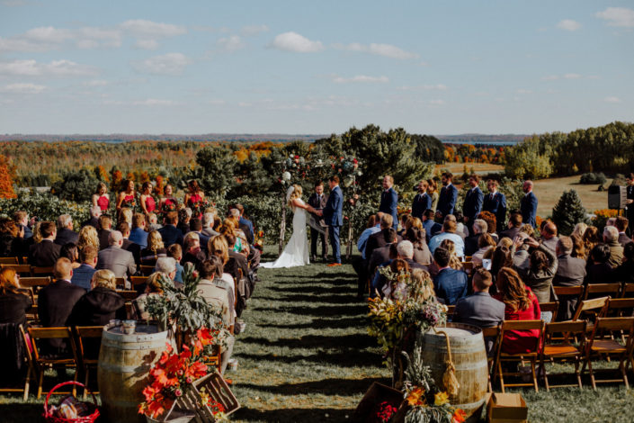 October wedding ceremony with couple and attendees atop our vineyard with beautiful fall colors.