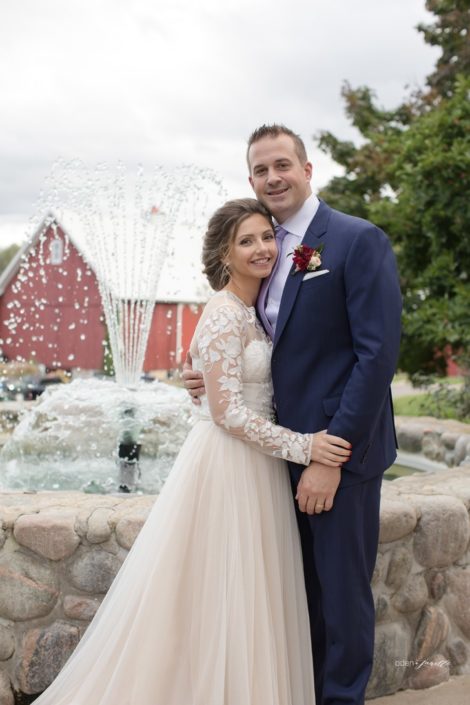 Bride and groom standing by the fountain at the Inn at Black Star Farms.