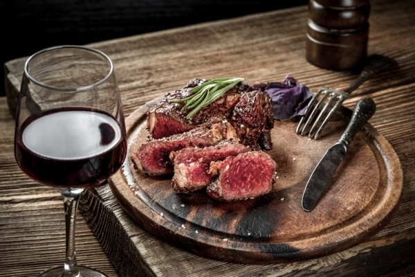 Grilled ribeye steak with a glass of red wine, one of the pairings suggested in the blog post.