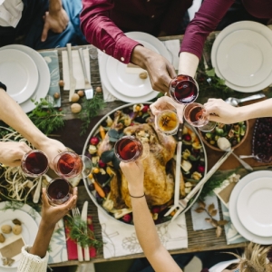 People clinking glasses over a Thanksgiving feast.