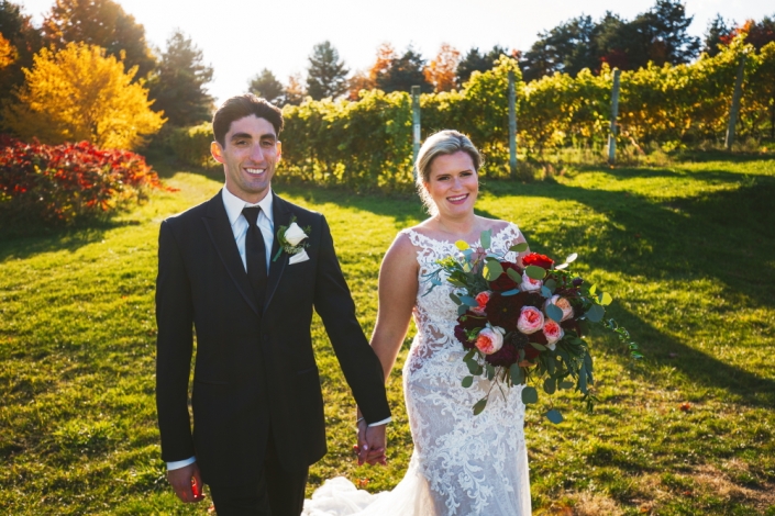 Bride and groom walking through the vineyard.