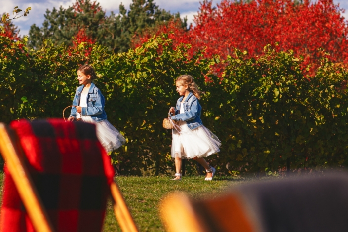 Flower girls walking by grape vines.