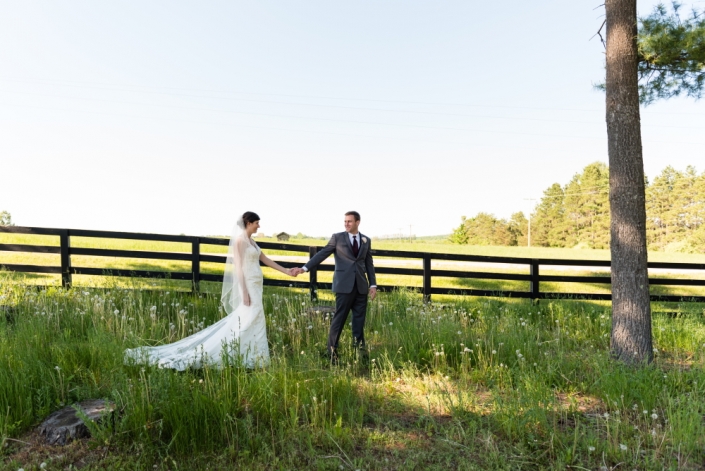 Bride and groom walking by a fence.