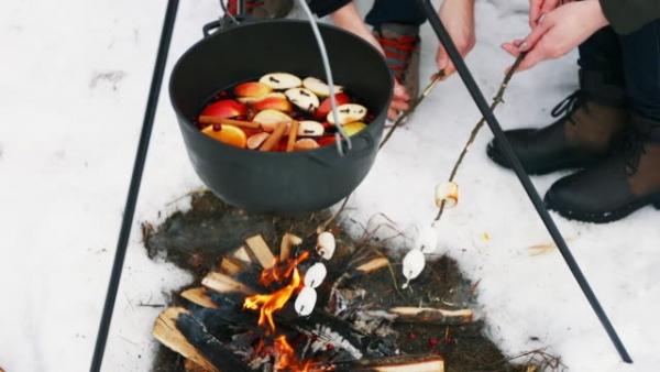 Heating mulled wine in a pot over a bonfire.