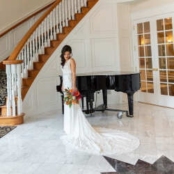 Bride standing near staircase and grand piano.