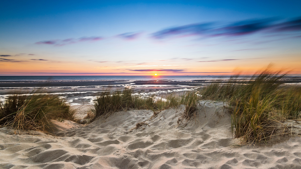 Take the Sleeping Bear Dunes Scenic Drive to see beautiful sunsets like this over the beach on the Sleeping Bear Dunes National Lakeshore