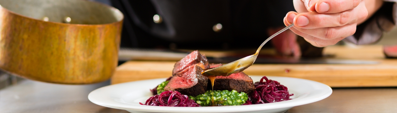 Chef pouring sauce over beef tenderloin.