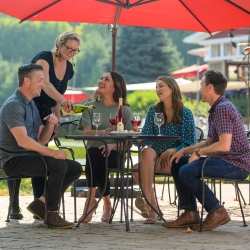 Woman pouring wine for guests on outdoor patio.