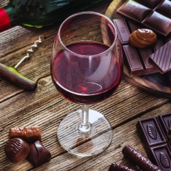 A glass of red wine with different chocolates.